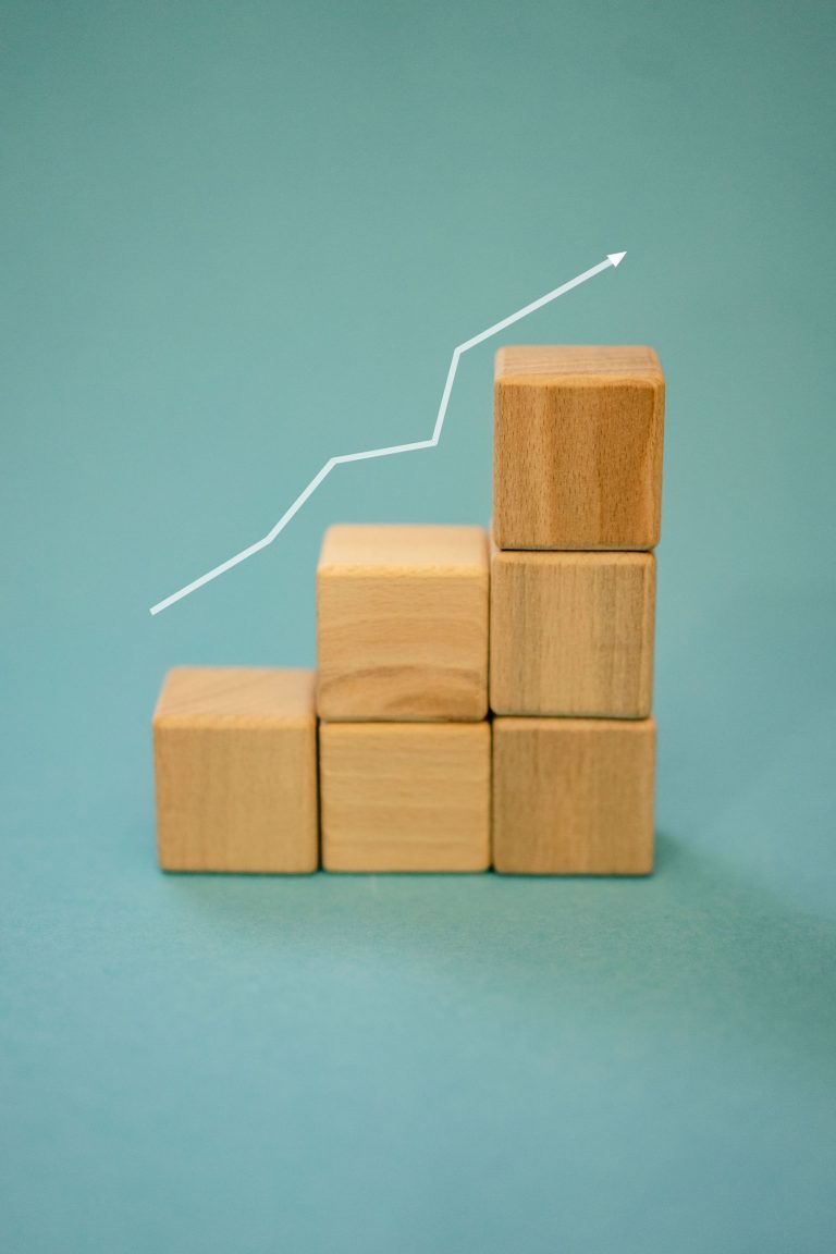 Wooden blocks forming an upward staircase with an arrow, symbolising business growth